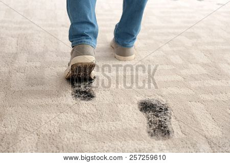 Person In Dirty Shoes Leaving Muddy Footprints On Carpet