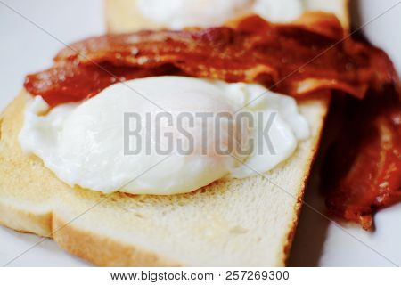 Poached Eggs With Crispy Streaky Bacon Served On White Toast
