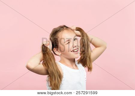 Happy Joyful Winking Adolescent Girl Making Pig Tails From Her Hair. Relaxed Carefree Lifestyle And 