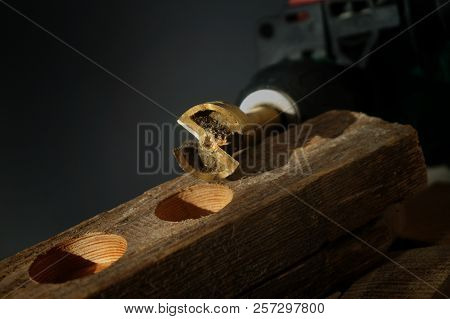 Close Up On Small Metal Tool For Drilling Circular Holes Sitting On Top Of Wooden Block Over Black B