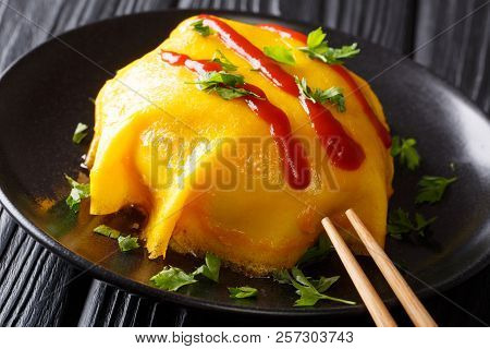 Tasty Omelette With Rice, Chicken, Vegetables And Tomato Sauce On A Black Plate. Horizontal
