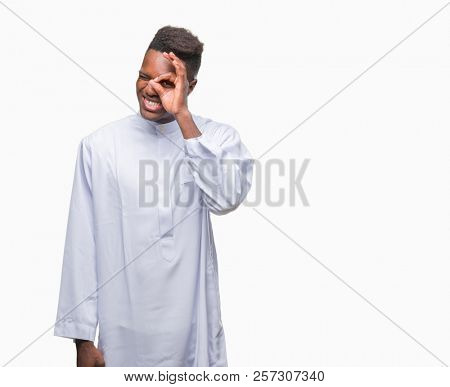 Young arabic african man wearing traditional djellaba over isolated background doing ok gesture with hand smiling, eye looking through fingers with happy face.