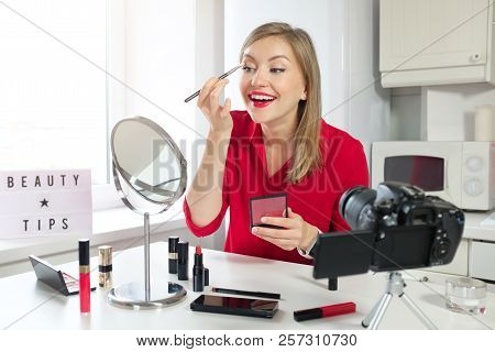 Stylish Girl Blogger In Red Blouse Drawing On Her Eyebrows, Looking At Mirror, While Recording Make 