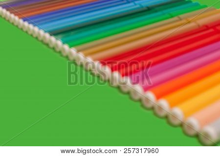 Row Of Various Bright Multicolored Felt Pens Lying On A Green Surface. Concept Of Creativity And Ima