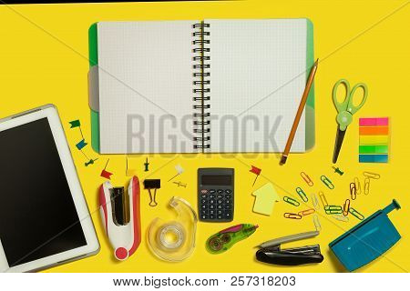 Multiple School And Office Suplies And Gadgets Lying On A Yellow Background