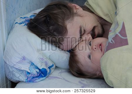 Little Baby Girl Wake Up In The Morning. Parent Tired Sleeping. Father Lying On Bed. Happy Family.
