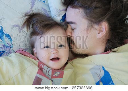Little Baby Girl Wake Up In The Morning. Parent Tired Sleeping. Father Lying On Bed. Happy Family.