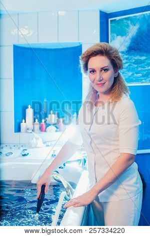 Young Woman During Hydromassage In Beauty Salon. Concept Of Body Care And Spa. The Masseuse Massages