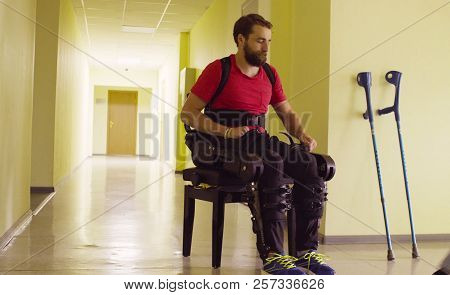 Disable Man In The Robotic Exoskeleton Sitting On The Bench