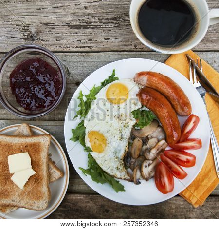English Breakfast. Eggs, Sausages, Mushrooms, Tomatoes, Toast Bread. Eating Tasy Food Over Rustic Wo
