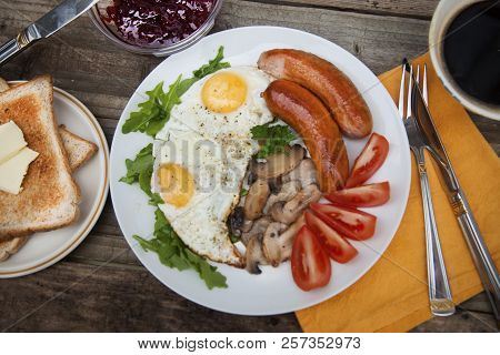 English Breakfast. Eggs, Sausages, Mushrooms, Tomatoes, Toast Bread. Eating Tasy Food Over Rustic Wo