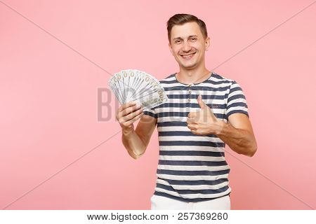 Portrait Of Smiling Excited Young Man In Striped T-shirt Holding Bundle Lots Of Dollars, Cash Money,