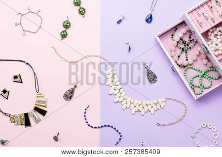 Open Jewelry Box With Neclaces, Earrings And Rings On Pastel Background. Top View