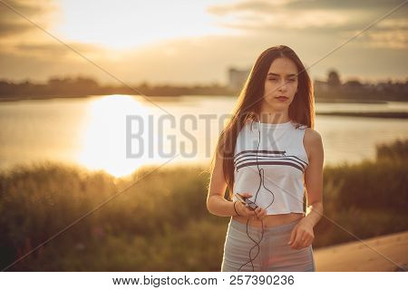 Young Beautiful Caucasian Girl Listening To Music With Smartphone Walking In The City With Headphone