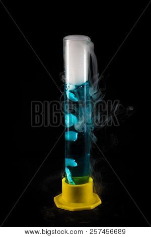 Closeup Of Steaming Test Tube With Blue Liquid Against Black Background, Chemical Experiment Concept