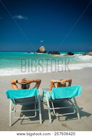Couple on sunbeds relaxing at the beach in Lefkada Greece