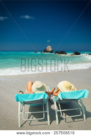 Couple on sunbeds relaxing at the beach in Lefkada Greece