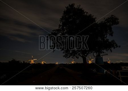 These Beautiful Windmills In Kinderdijk Are Illuminated With White Light At The Blue Hour