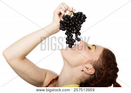 Beautiful Redhead Woman Is Eating Black Grapes. Concept Of Healthy Eating