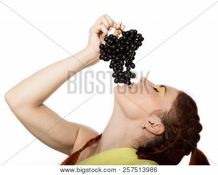 Beautiful Redhead Woman Is Eating Black Grapes. Concept Of Healthy Eating