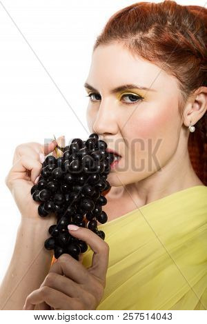 Beautiful Redhead Woman Is Eating Black Grapes. Concept Of Healthy Eating