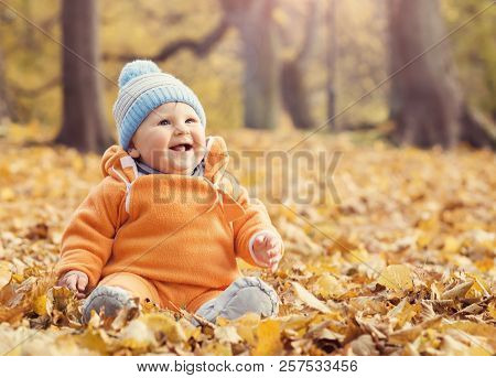 Happy Toddler Baby Playing With Leaves In Autumn Park.