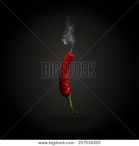 Red Hot Chilli Pepper With Smoke Coming Out Of It. Dark Black Ba