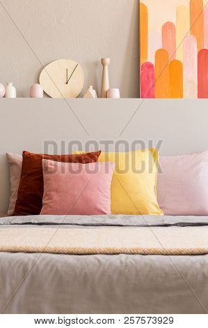 Real Photo Of Bed With Colorful Pillows In Bright Room Interior With Minimal Clock, Decor And Arcade
