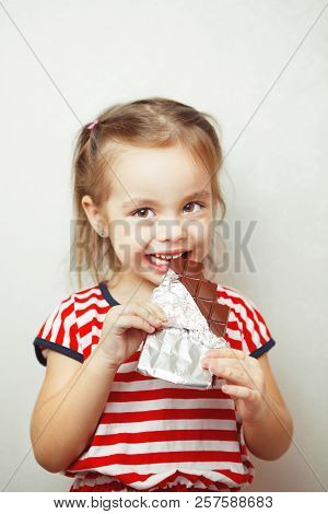 Lady Of Young Age Eating Chocolate Wrapped In Tinfoil