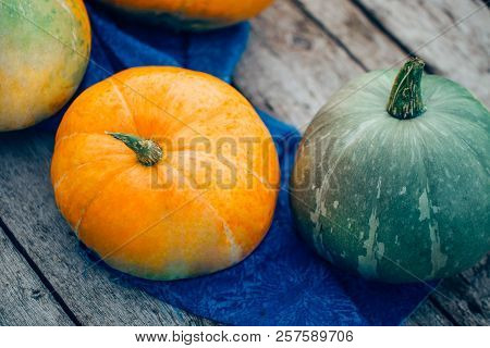 Green And Orange Pumpkins On Wooden Background
