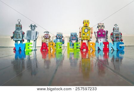  WE ARE LEARNING wooden letters and retro robot toys on a wooden floor with reflection