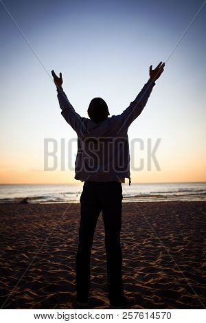 Man Silhouette With Hands Up At The Sunset Background