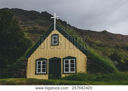 Hofskirkja Yellow Church In Town Of Hof With Mountain Behind In Iceland