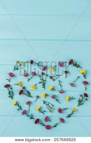 Colorful Flowers Composition In Shape Of Heart. Blue Wooden Background. Top View, Flat Lay.