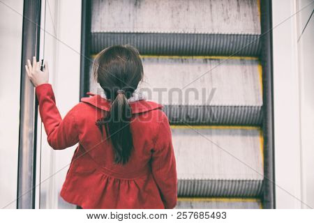 Woman commuter going to work walking up escalator stairs commuting in train station or airport.