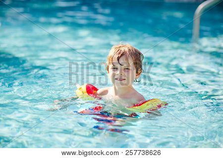 Happy Little Kid Boy Having Fun In An Swimming Pool. Active Happy Child Learning To Swim. With Safe 