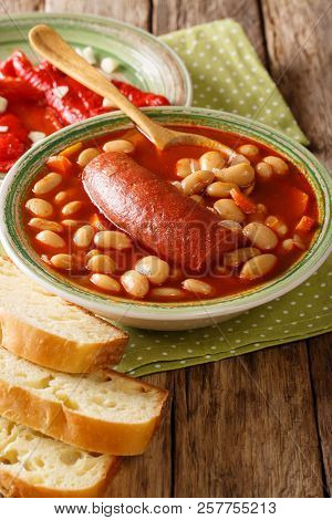 Delicious Pasulj Bean Soup With Sausage Served With Pickled Pepper And Bread Close-up. Vertical