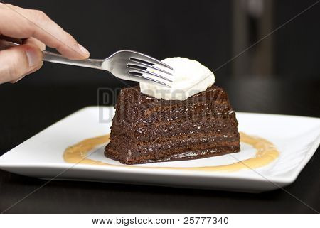 Hånd, der holder gaffel om til skive i en chokolade Marquise med hvid chokolade Marscapone og Butte