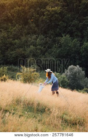 Girl In A Hat Playing With A Dog In The Field At Sunset Sun