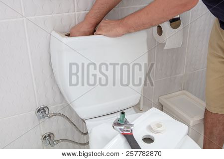 Man Using Hands Repairing Toilet Cistern In A Concept Of Diy Repairs With Copy Space