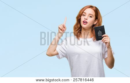 Young beautiful woman holding passport of canada over isolated background surprised with an idea or question pointing finger with happy face, number one