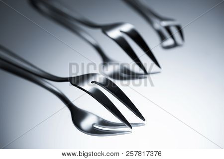 Close-up View Of Forks With Two Tines Reflected On Grey