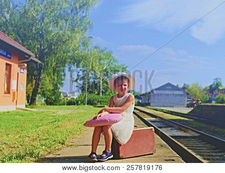 Adorable Little Girl On A Railway Station, Waiting For The Train With Vintage Suitcase. Traveling, H