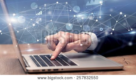 Businessman typing on laptop with linked reports charts grapghs around