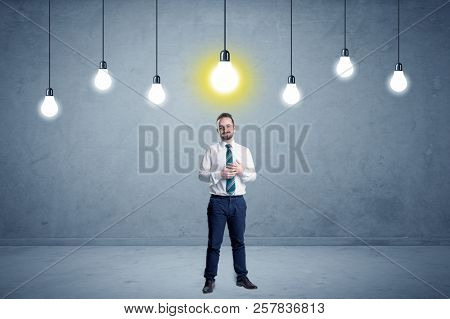 Handsome businessman in an empty space with bulbs above and uninspired face