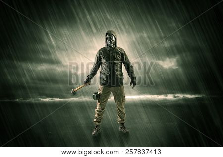 Terrorist in a stormy space with gas mask on his hand and weapons on his arm