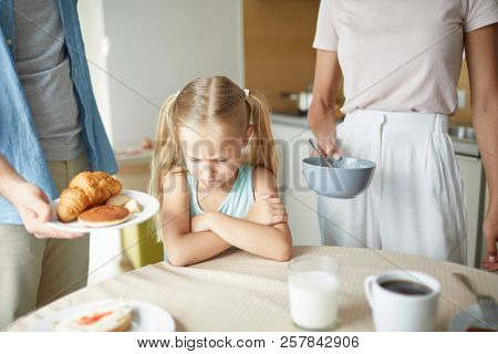 Capricious little girl does not want to eat anything her parents offering for breakfast