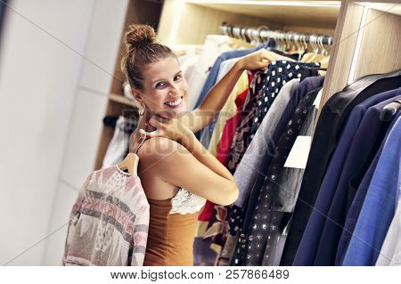 Beautiful woman thinking what to dress in walk-in closet