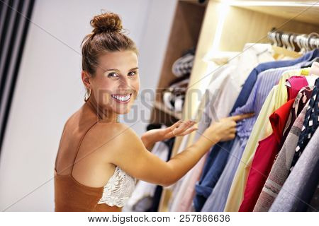 Beautiful woman thinking what to dress in walk-in closet
