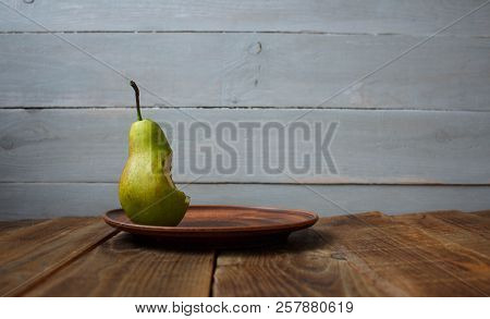 A Bite Pear On A Plate On Wooden Background